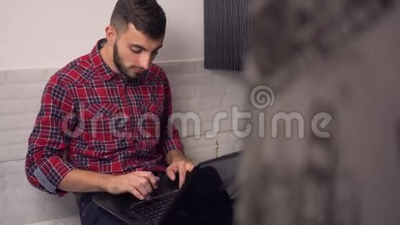 有魅力的年轻人在厨房的笔记本电脑上工作视频的预览图