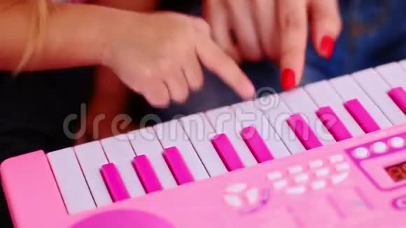 特写小女孩按着粉色钢琴的键视频的预览图