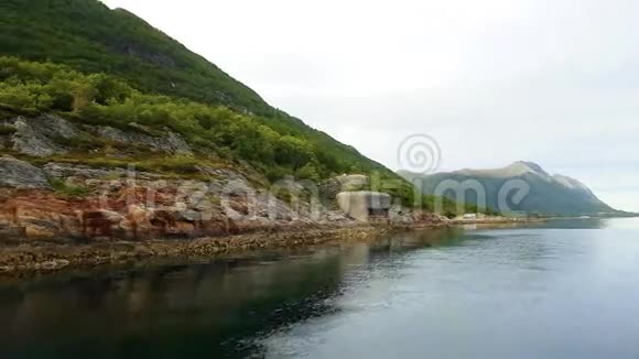 游艇沿着绿色的丘陵海岸航行在挪威某处平静的水域中携带第二次世界大战的药丸视频的预览图