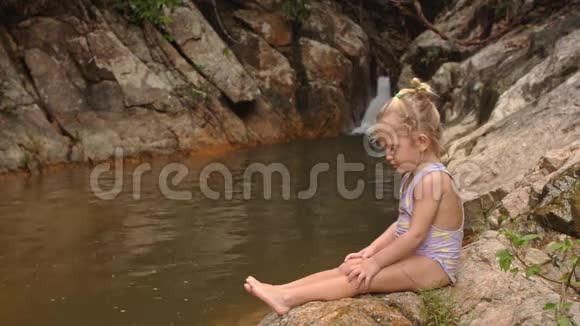 小金发女郎用瀑布把清洁脚踩在石头上视频的预览图