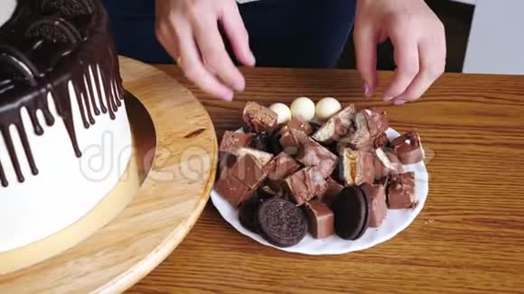 女人手的特写装饰一个蛋糕上面有巧克力和椒盐卷饼坚果视频的预览图
