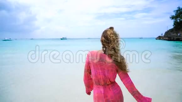海滩上的女人在日落时穿着裙子跑来水在暑假旅行中举起手臂享受自由视频的预览图