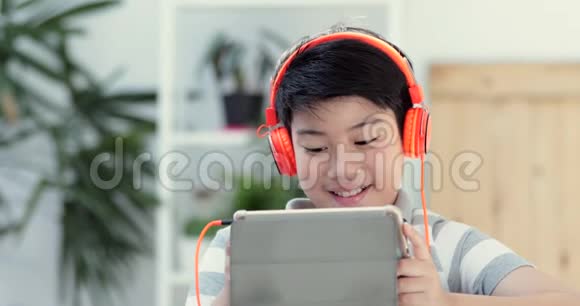 接近亚洲青少年前玩平板电脑与微笑的脸在家视频的预览图