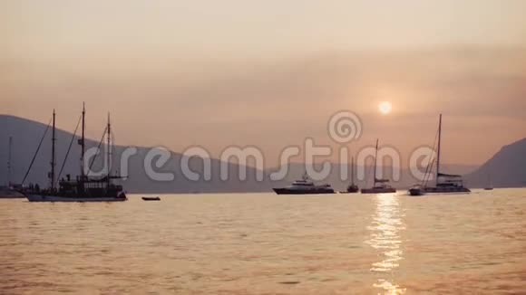 美丽的日落和宁静的海面几艘船游艇和山山的背景没有视频的预览图