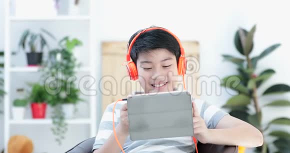 接近亚洲青少年前玩平板电脑与微笑的脸在家视频的预览图