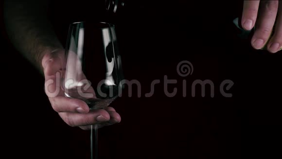 一个人把酒倒在黑色背景上的杯子里慢动作视频的预览图