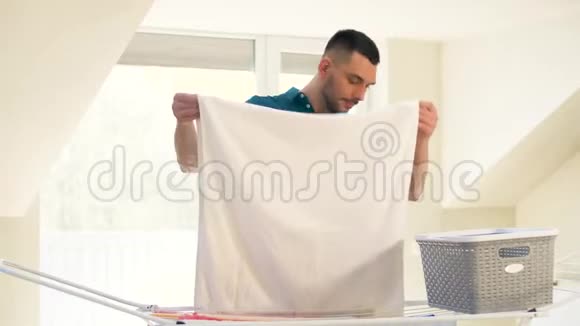 从家里的晾衣架上拿衣服的男人视频的预览图