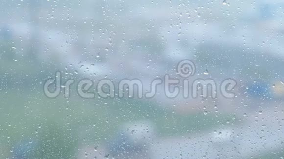 雨滴沿着窗户的特写从潮湿的窗户看城市和道路模糊视频的预览图