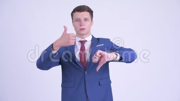 困惑的年轻商人在竖起大拇指和竖起大拇指之间做出选择视频的预览图