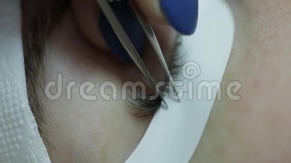 美容师为美丽的女孩增加睫毛睫毛延伸手术特写视频的预览图
