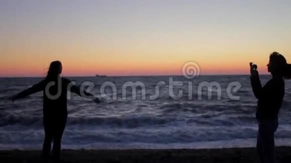 妈妈让女儿在海上日落时拍照手持射击视频的预览图
