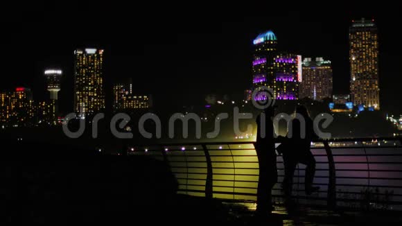 夜晚城市摩天大楼背景下的男女剪影视频的预览图
