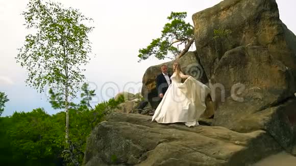 一对夫妇爬上岩石欣赏日出日落慢动作视频的预览图