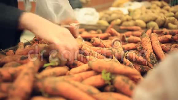 一个女人在蔬菜货架上的超市里买蔬菜和水果男人选择胡萝卜视频的预览图