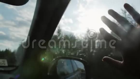 阳光透过手指和树木车上车窗上戴着戒指手指掌特写镜头慢节奏视频的预览图