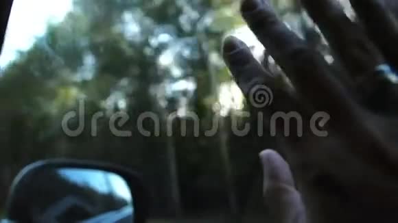 阳光透过手指和树木车上车窗上戴着戒指手指掌特写镜头慢节奏视频的预览图