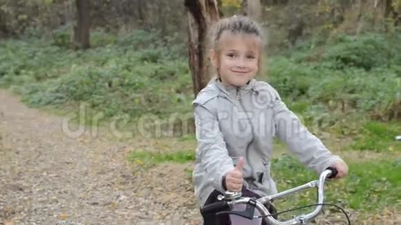 秋天的森林里一个快乐的小女孩骑着自行车视频的预览图