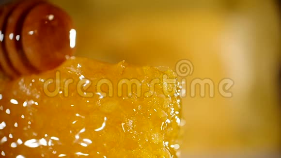 蜂蜜滴在蜂窝上黄色背景从木制蜂蜜中浸泡出厚的有机蜂蜜视频的预览图