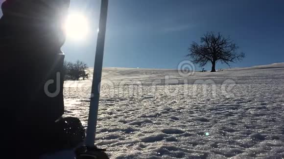 穿着雪鞋在冬天的风景中行走的人的剪影带着徒步旅行杆蓝天和视频的预览图