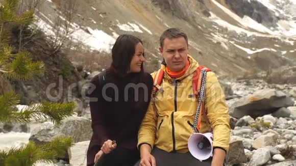 美丽的夫妇坐在山上的石头上欣赏风景视频的预览图