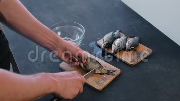 人从木板上的鳞片上清洁鲤鱼特写双手做一条鱼视频的预览图