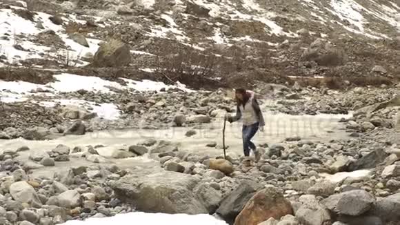 美丽的年轻旅人沿着山河漫步群山环绕视频的预览图