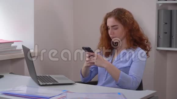 肖像红头发女性使用智能手机视频的预览图