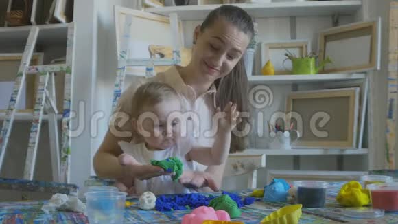 年轻迷人的母亲和可爱的小女儿妈妈和小女孩用塑料做模特视频的预览图