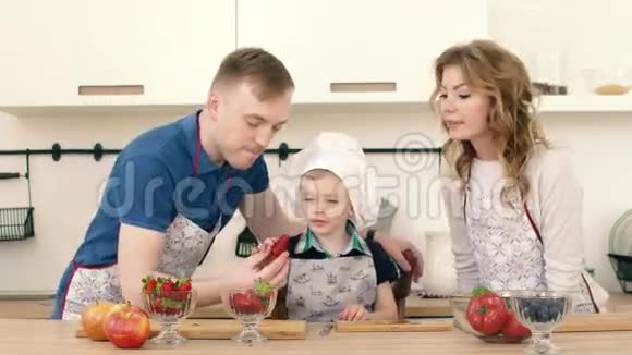儿子用草莓招待父母他们在厨房准备一份水果沙拉视频的预览图