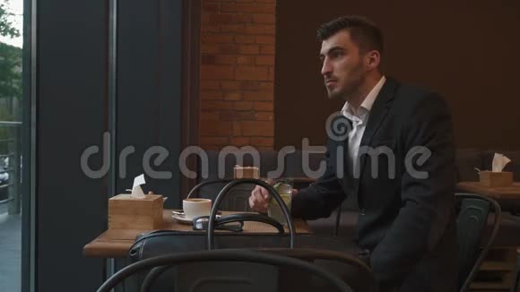 年轻英俊的商人穿着燕尾服喝柠檬水在炎热的夏天凉快现代咖啡馆背景视频的预览图
