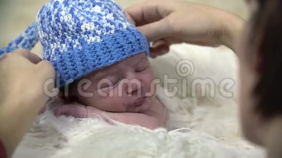 把蓝色的帽子贴在婴儿头上的近镜头视频的预览图