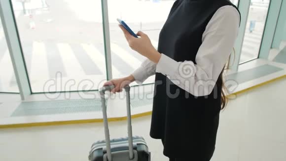 女游客在国际机场航站楼携带行李使用智能手机语音识别短信命令视频的预览图