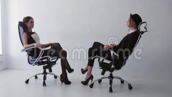 两个漂亮的女孩坐在办公室的椅子上视频的预览图