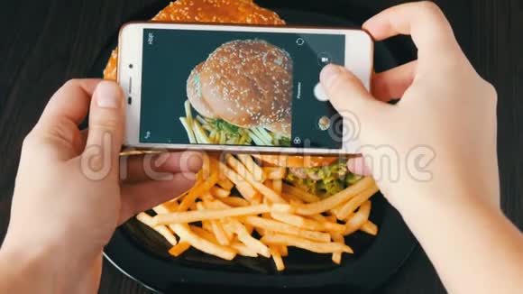 女性手在盘子上制作一个大汉堡的智能手机照片快餐图片视频的预览图