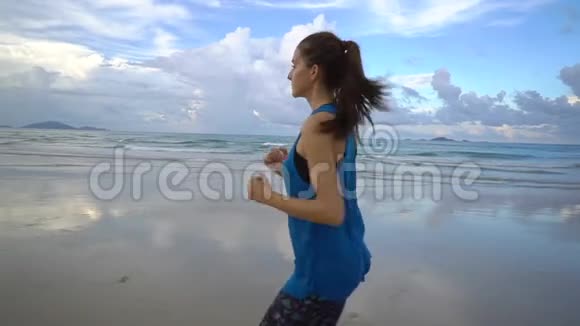 运动的女跑步者在海滩上慢跑穿运动装的年轻女性视频的预览图