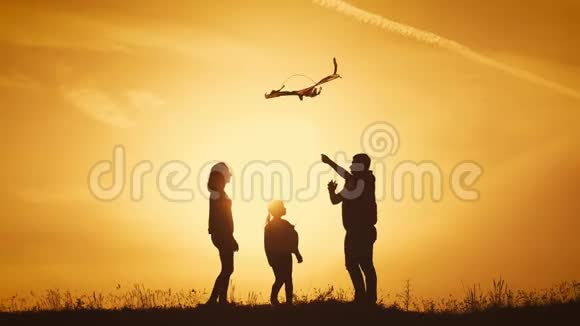 快乐的一家人在草地上玩风筝日落在夏日有趣的家庭时光快乐小女孩推出视频的预览图