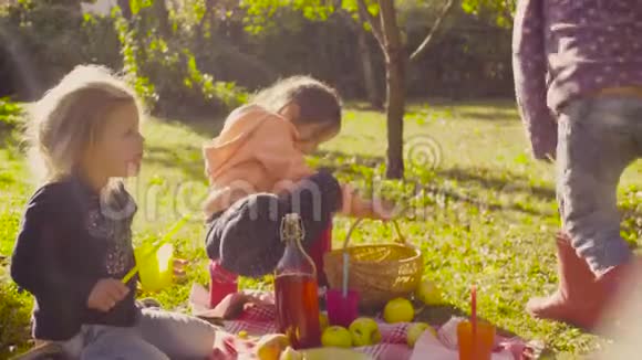 在花园里野餐坐在草地上喝酒的孩子们视频的预览图