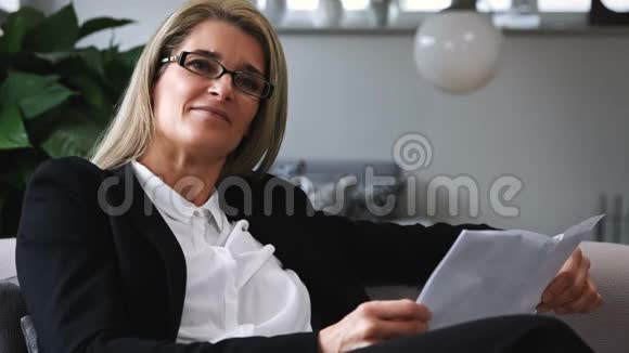 商务女性坐在沙发上看文件视频的预览图