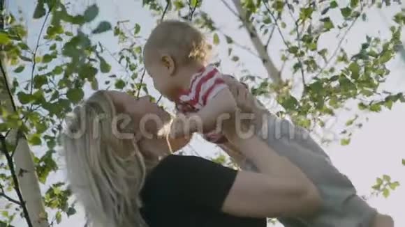 迷人的母亲抱着小儿子在怀里俄罗斯桦树作为背景慢动作4k视频的预览图