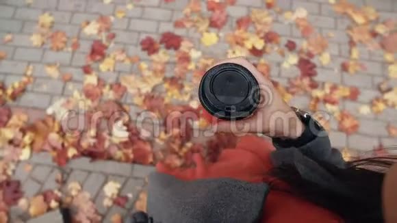 秋天年轻时尚的女士带着智能手表端着一杯咖啡秋天美丽的枫叶视频的预览图