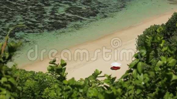 在巴厘岛美丽的热带海滩上孤独的伞和蓝色的海浪视频的预览图