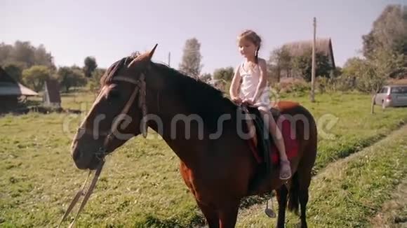 在阳光明媚的日子里一个快乐的小女孩在大自然中骑马她在微笑玩得很开心慢点视频的预览图