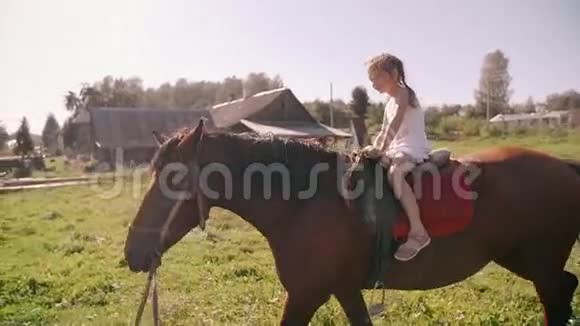 在阳光明媚的日子里一个快乐的小女孩在大自然中骑马她在微笑玩得很开心慢节奏视频的预览图