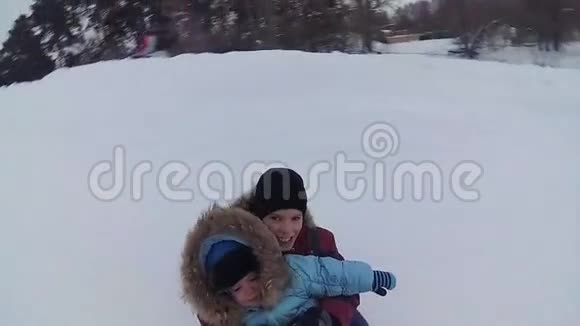 一个快乐的孩子在白雪覆盖的道路上的雪管里骑车微笑视频的预览图