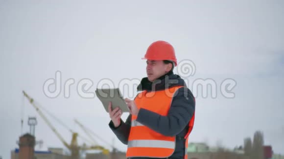 建筑设计师戴着头盔在施工现场用平板电脑建筑业工人冬季建筑视频的预览图