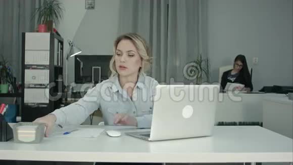 年轻的办公室秘书在手提电脑和接电话视频的预览图