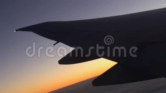 在天空和云层中的日落背景上的机翼飞机视频的预览图
