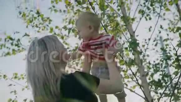 迷人的母亲抱着小儿子在怀里俄罗斯桦树作为背景慢动作4k视频的预览图