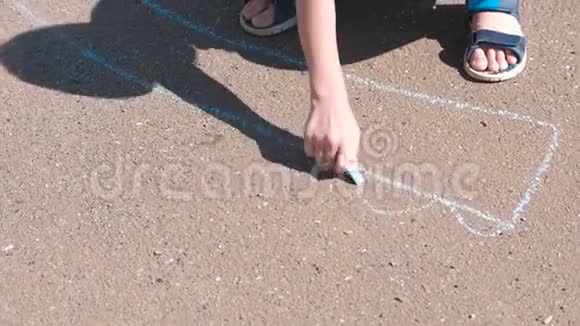 男孩在沥青上用蓝色粉笔画画特写双手视频的预览图