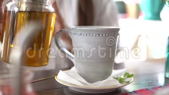 女人把茶从茶壶倒到杯子里视频的预览图